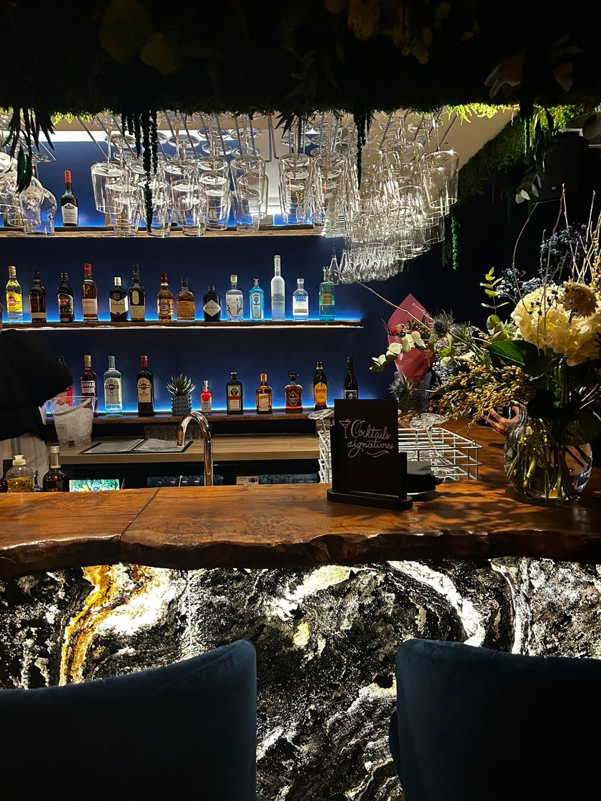 Le bar du Felicia Deauville — comptoir en bois massif, éclairages bleus, cocktails signatures et verres suspendus